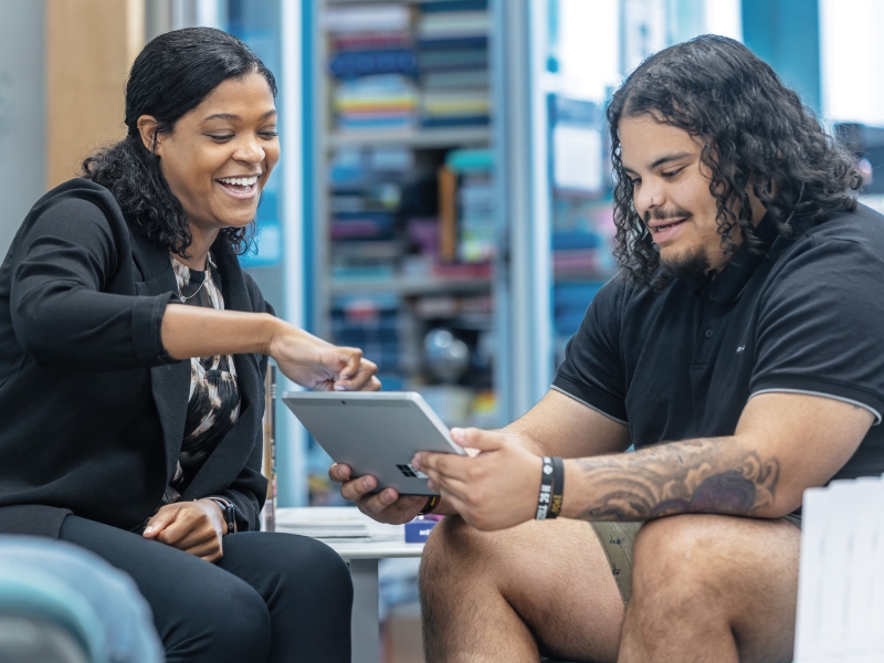 a student and professor looking at a laptop together