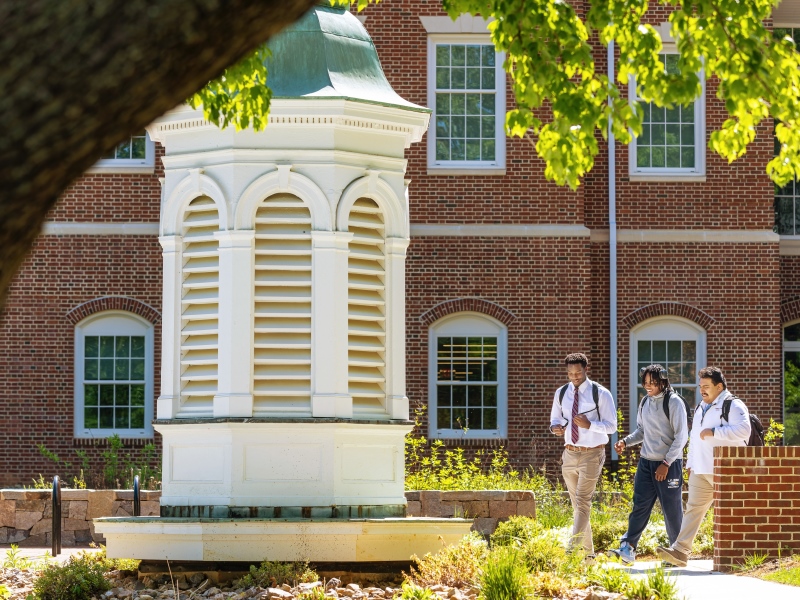 Three students walking past the Bagby cupola