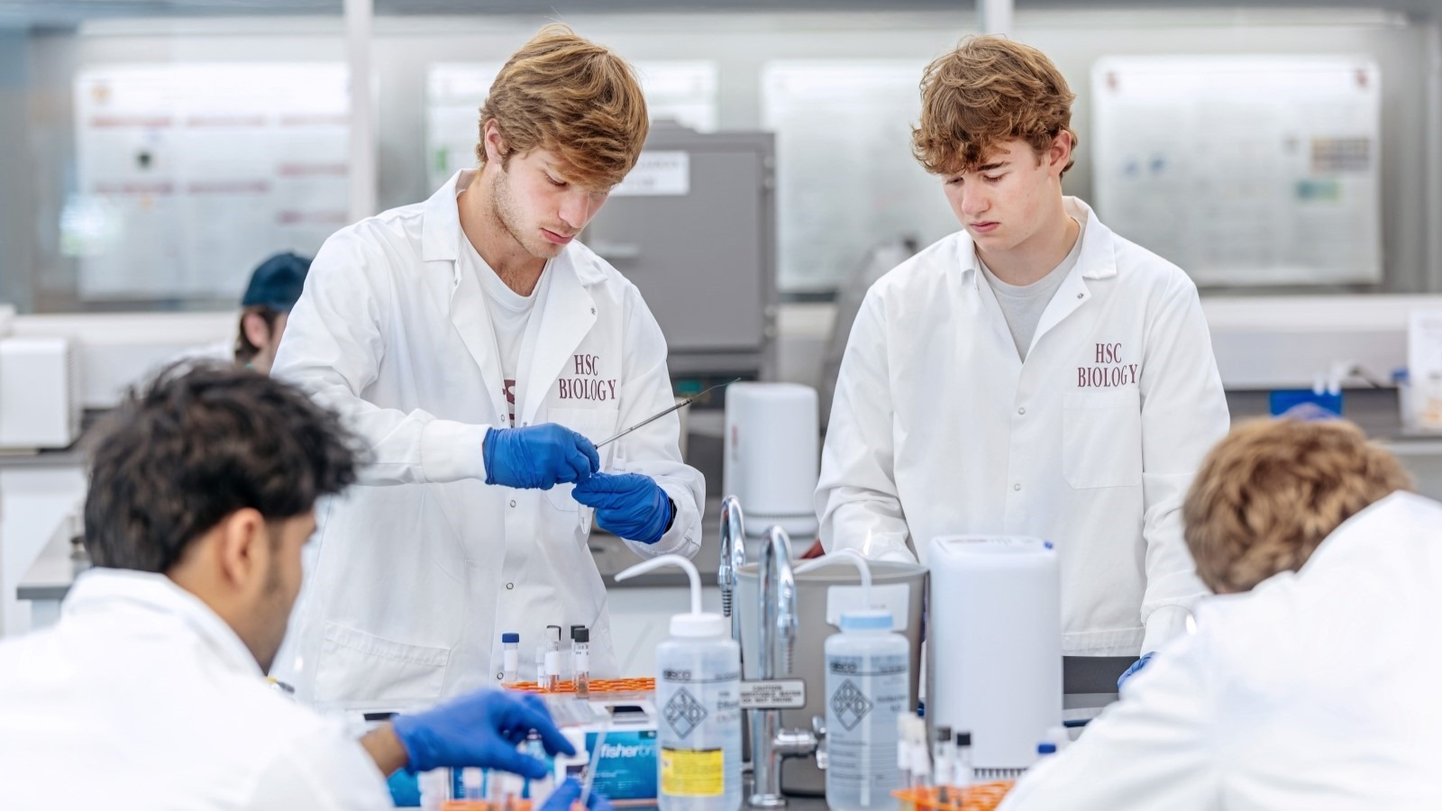 students in laboratory coats doing research in the bio lab