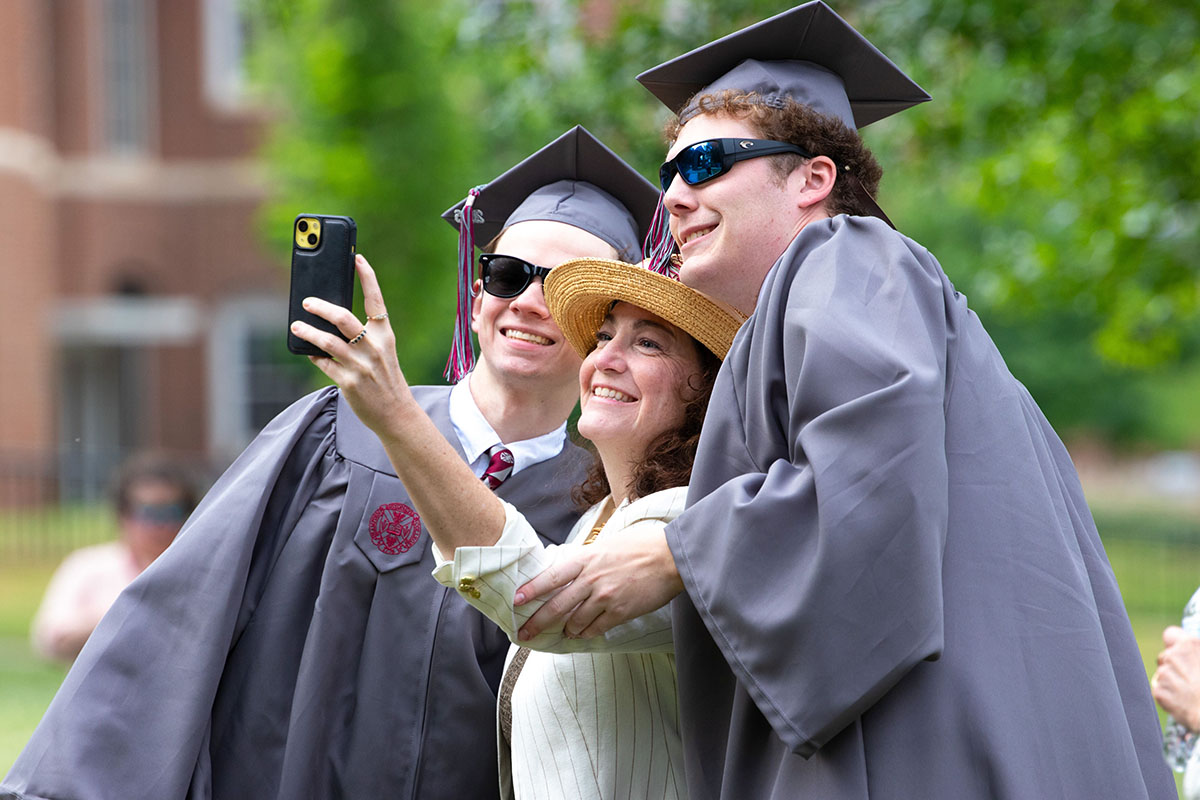 a graduate and his mother posing for a selfie after the commencement ceremony