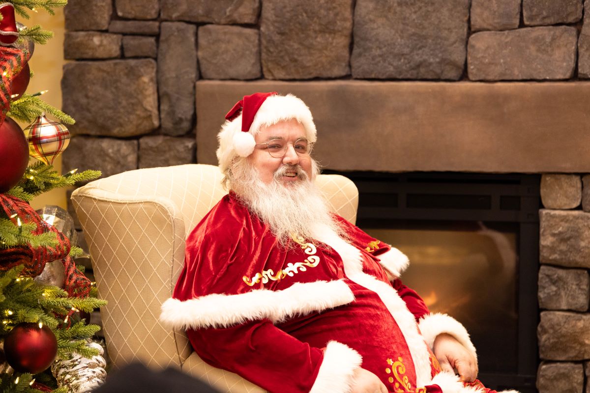 Santa posing for a photo in front of the hearth in the student center
