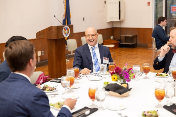 H-SC alumnus laughing and talking at a table at a large dinner gathering