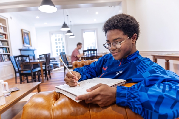 Student sitting on a couch studying his notebook