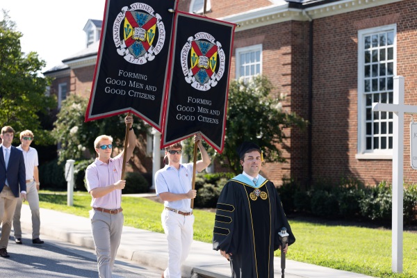 Dean of Students and students processing with flags to convocation