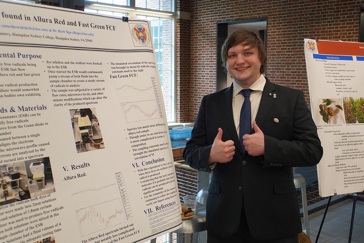 A student standing beside his research poster presentation at Hampden-Sydney College