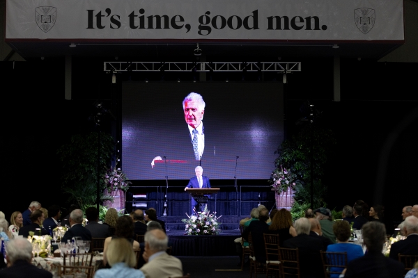 President Stimpert addressing the event crowd with "It's Time Good Men" campaign slogan behind him
