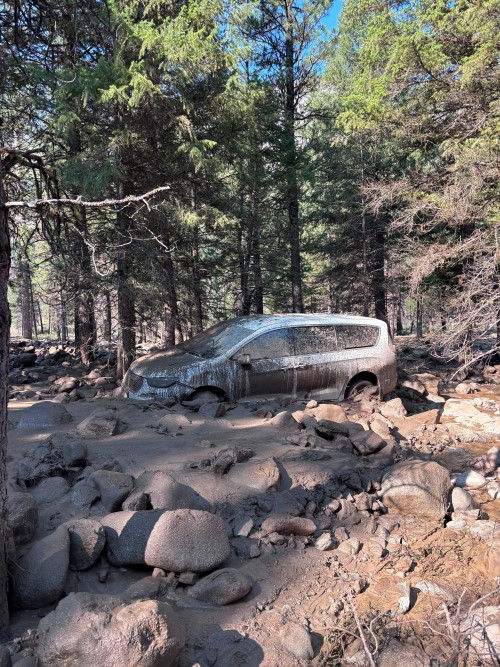 A car covered in mud in a river basin after a flood in the Idaho wilderness