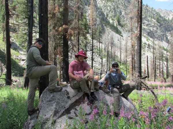 A few students sitting on a rock in the Idaho wilderness on an expedition