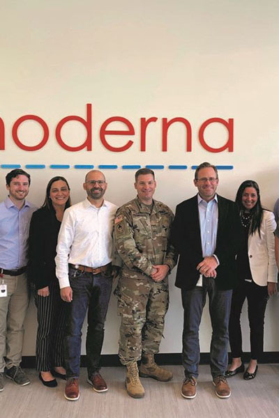 Scott Nickerson '95 standing with colleagues in front of a Moderna sign