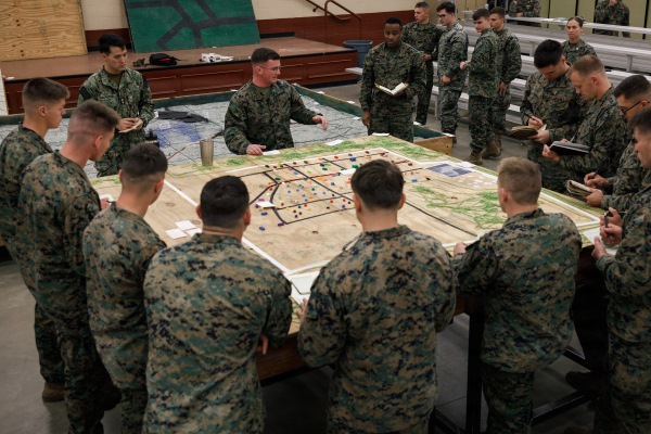 Zachary Toney standing around a map with students during a warfighting field exercise