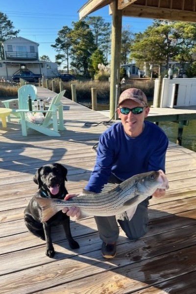 Rick Godsey holding a fish he caught with his dog