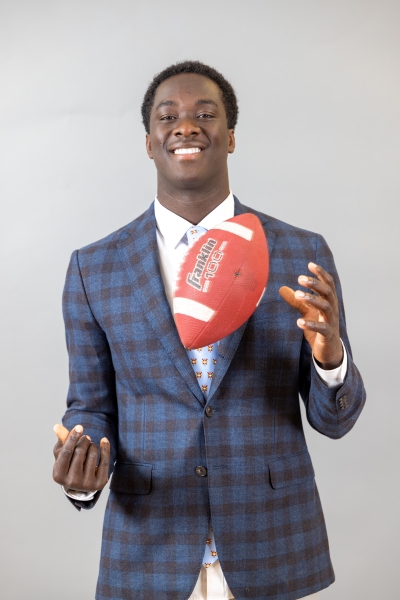 Carter Sido ’26 in a suit jacket holding a football