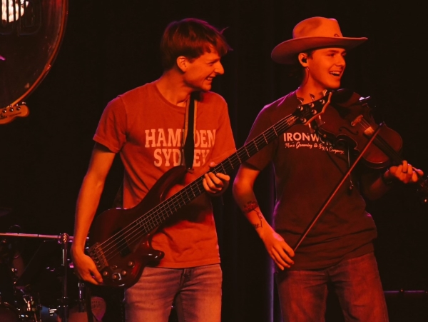 Haden VonCanon playing fiddle with a friend onstage under red lights