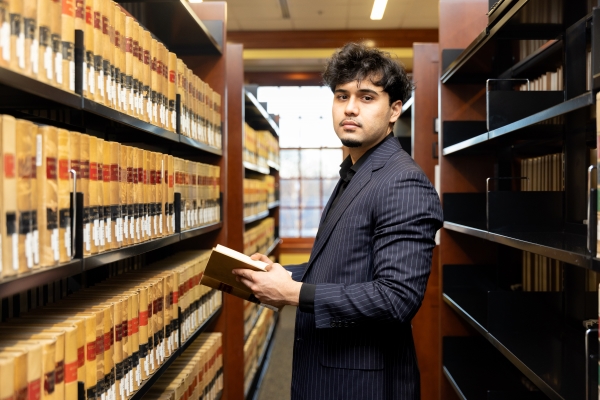 Kamal Iqbal holding a book in the library stacks