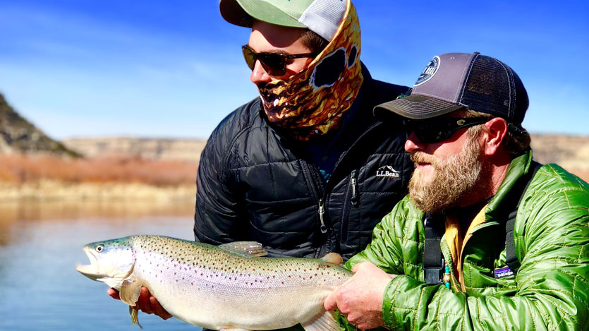 two men holding a trout