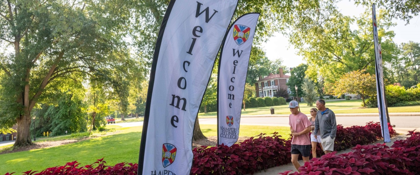 students walking up a sidewalk surrounded by welcome signs