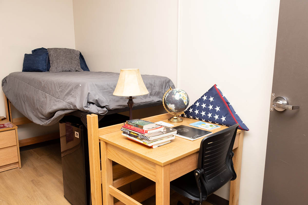 a bed and table inside a Carpenter residence hall dorm room