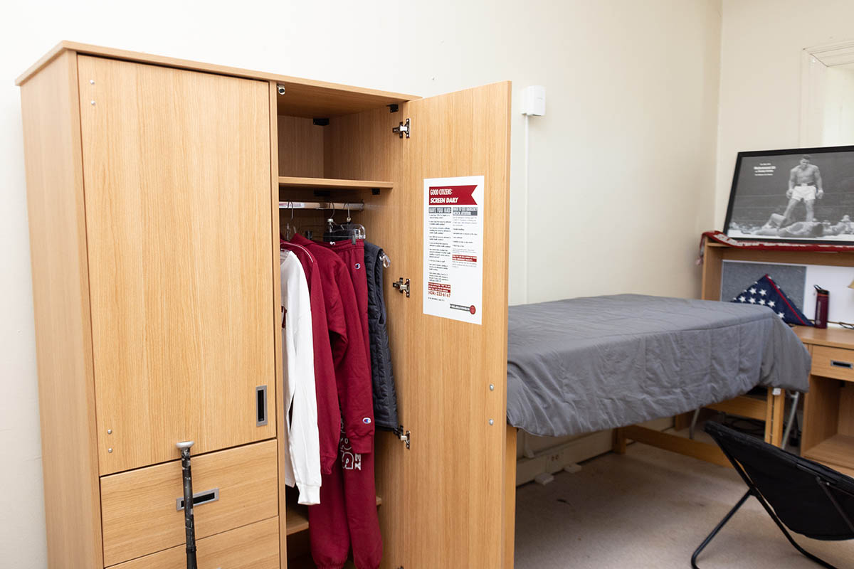 a bed and a wardrobe inside a dorm room in Cushing Hall