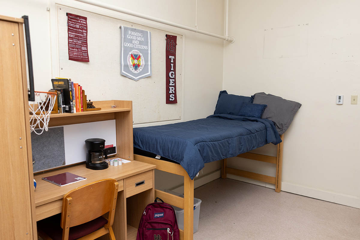 a bed and a table inside a dorm room in Cushing Hall