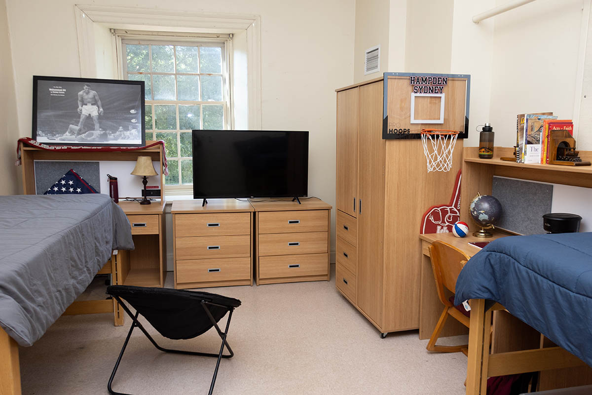 two beds and a table inside a dorm room in Cushing Hall