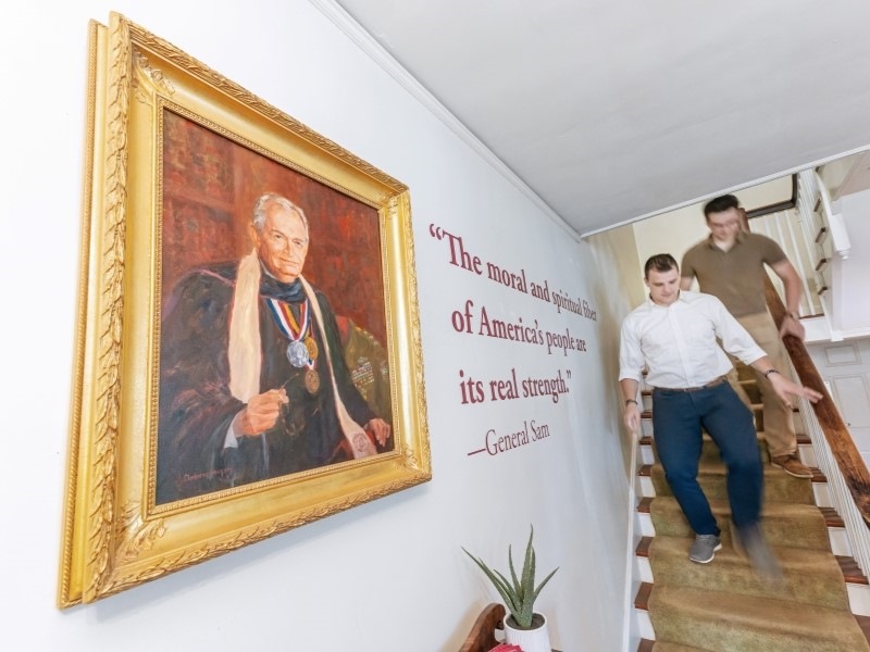 men walking down stairs with a portrait of Sam Wilson in the foreground