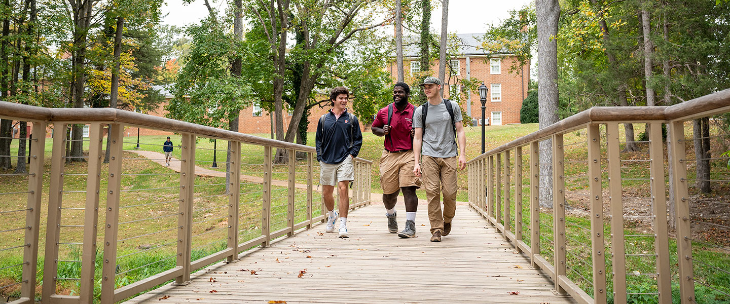 Students walking across a bridge and talking at Hampden-Sydney College.