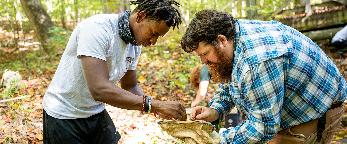 Biology Professor and student examining specimens in a creek