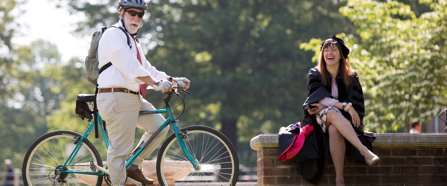 Professor on a bike and laughing with a colleague at Hampden-Sydney College commencement