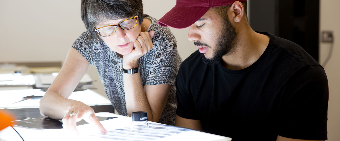 Professor Fox examines negatives with a photography student