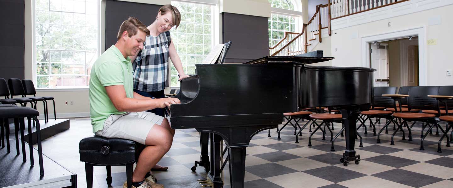 von Rueden points out a key note to a student on the piano