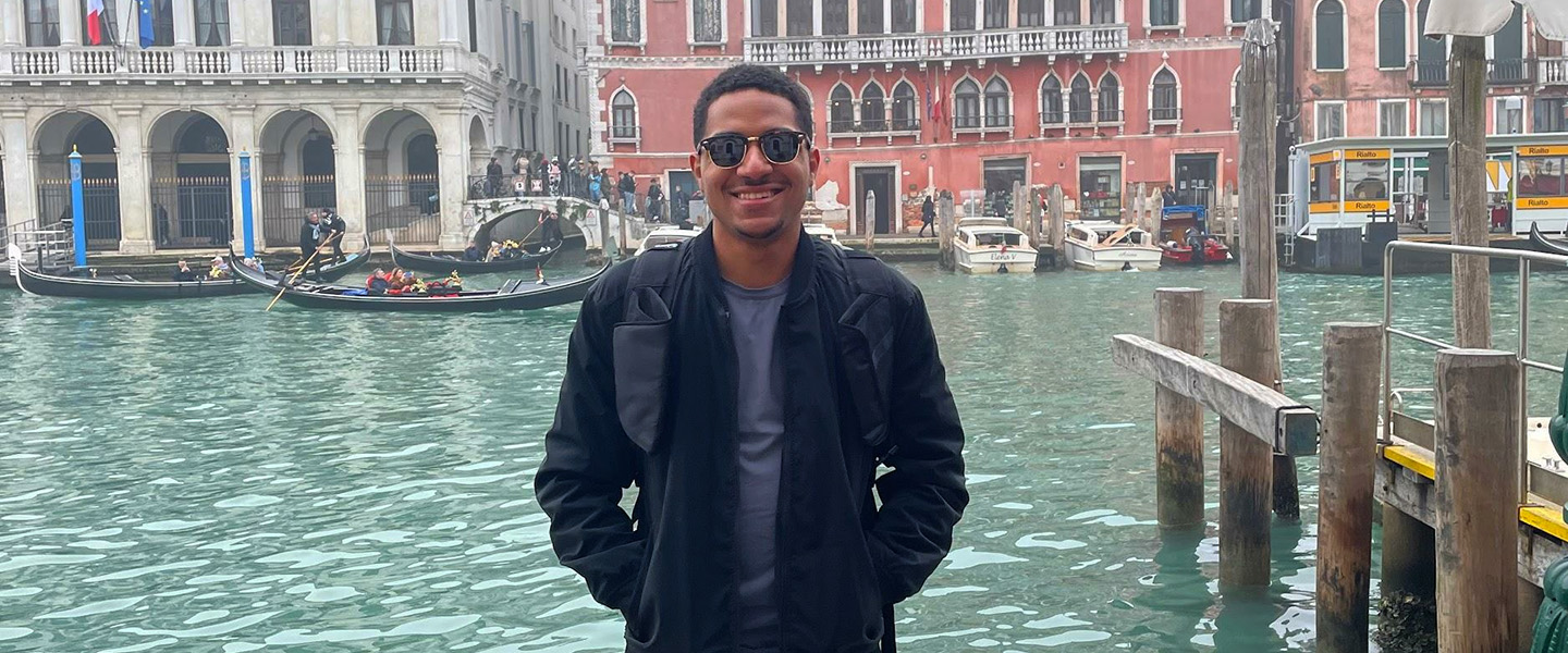 student standing in front of a Venecian river