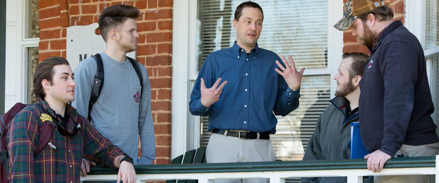 Professor Dinmore talking with history students on The Maples porch