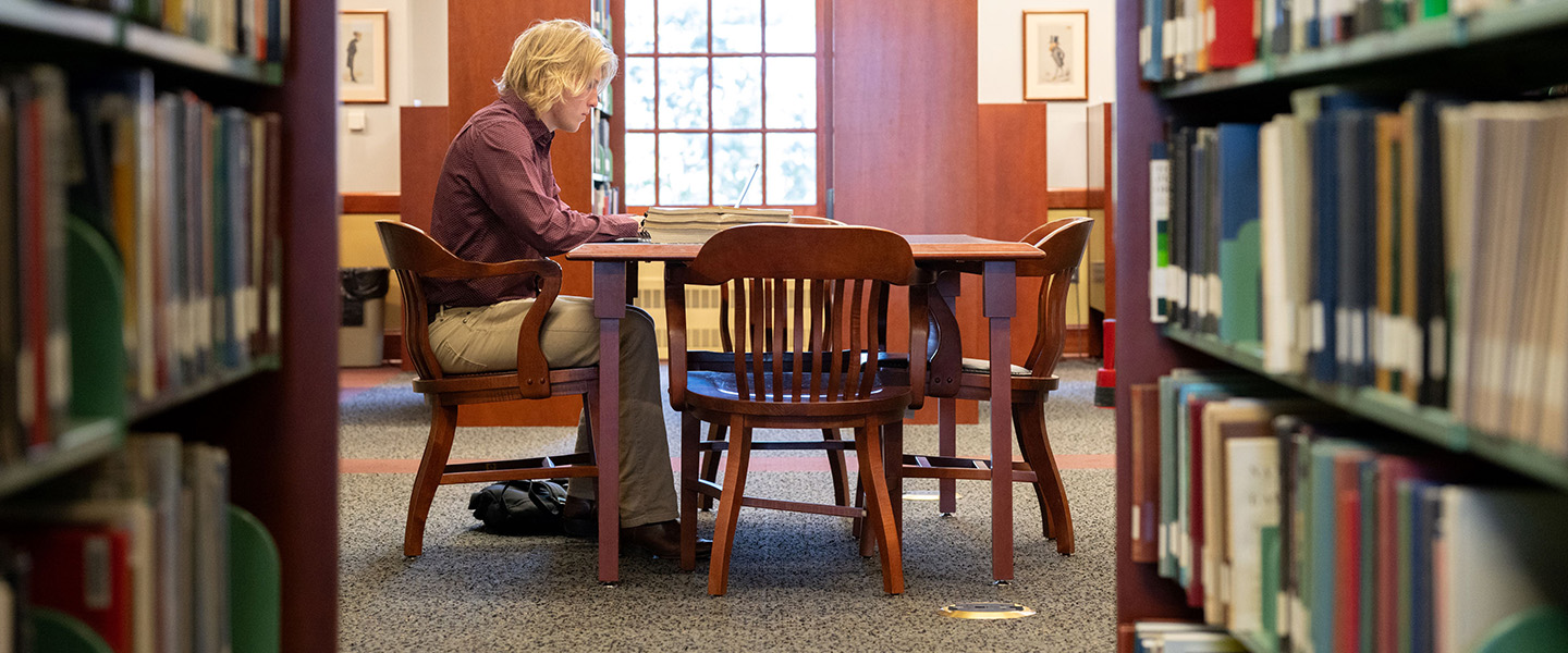 A student sitting at a table reading in the library