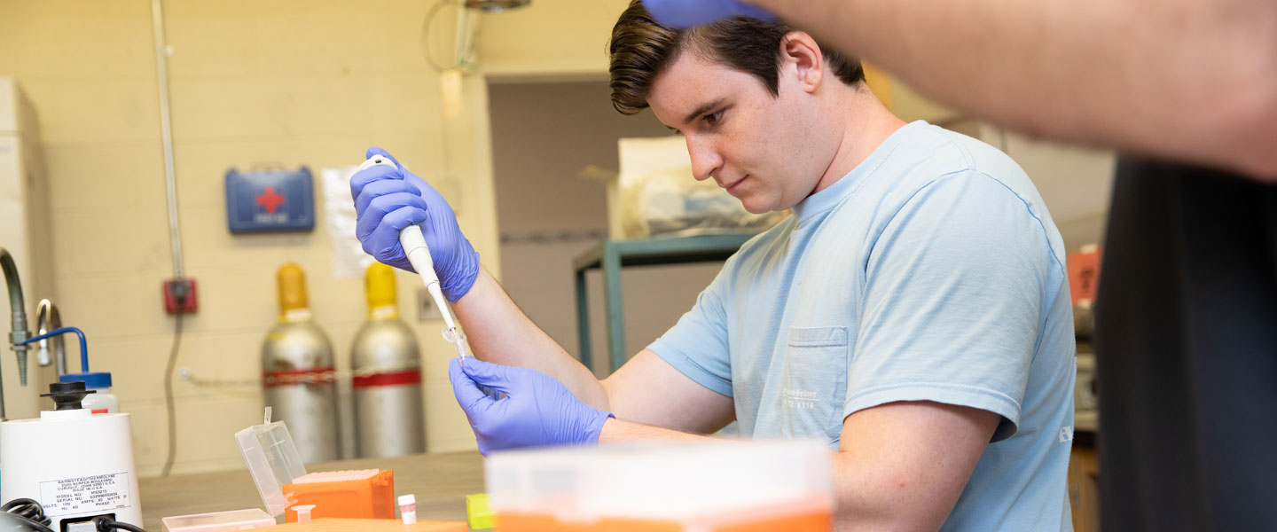 Student Corey Williams examining a sample in a biology lab at Hampden-Sydney College