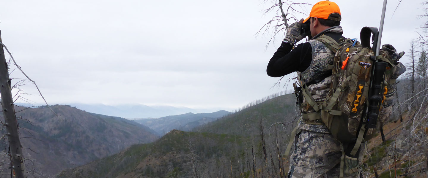 Michael Luter '94 looks through binoculars over a mountain valley.