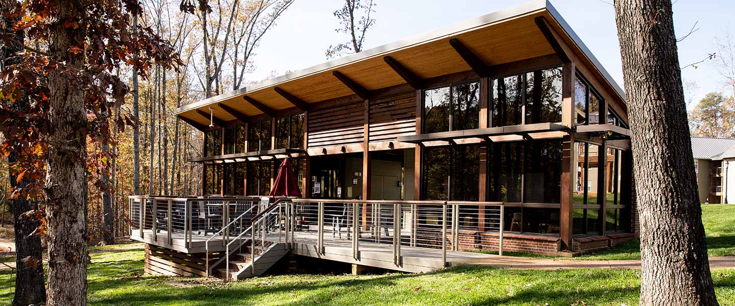 The Groves Residence Hall community building in the trees overlooking the pond