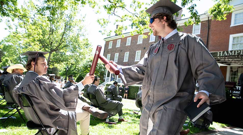 Commencement 2021 graduates tap their diplomas together as the process