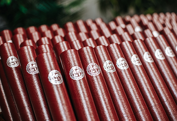 a row of diplomas in their garnet tubes
