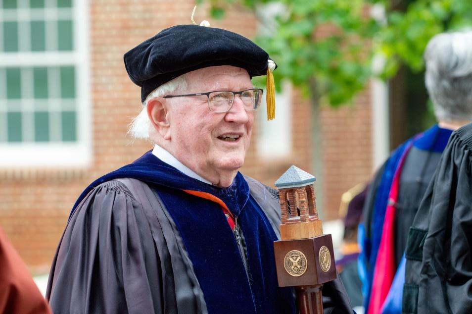 a professor in regalia leads the procession