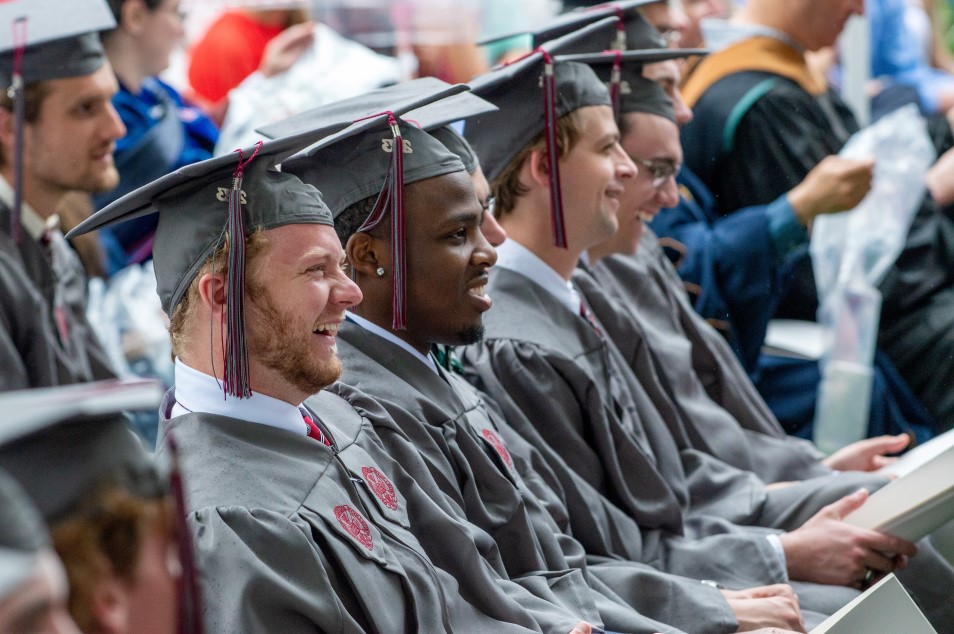 students smiling in their seats at commencement