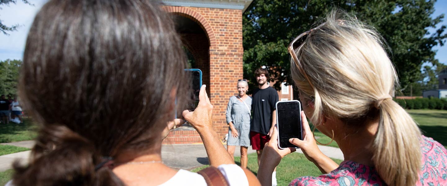 Family and friends taking photos of students in front of the Bell Towerat Hampden-Sydney College