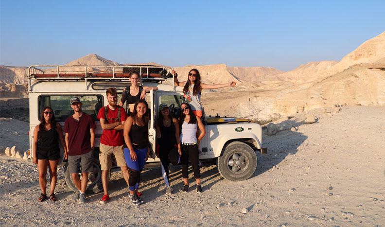Austin Senecal with a group of friends in front of an SUV in the Negev Desert