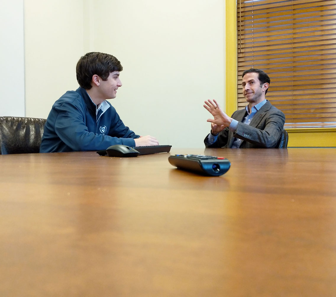 Dr. Andrew King consulting a student at a boardroom table