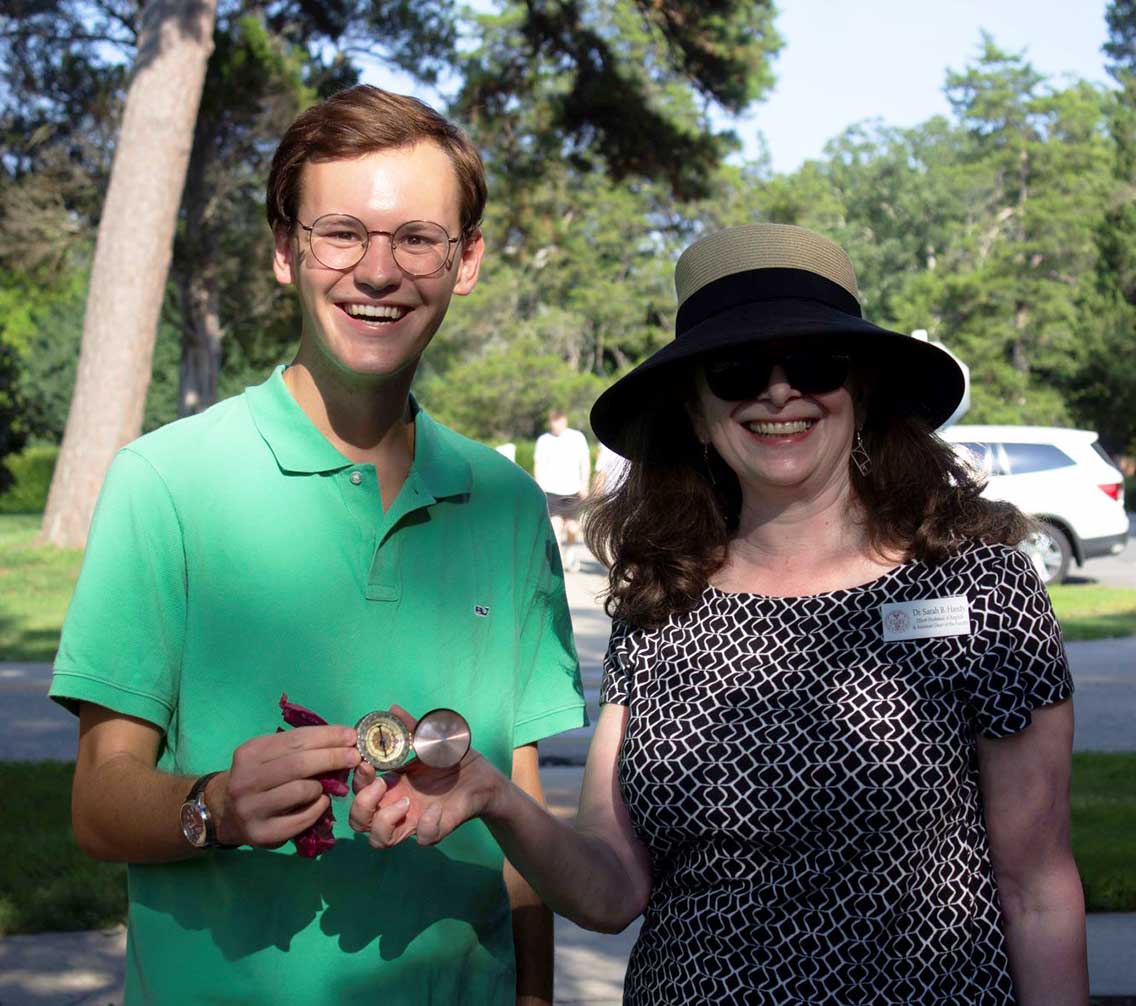 Nate Joyner '23 holding a compass and Dr. Sarah Hardy standing under a tree