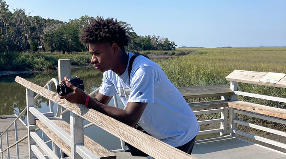 a student standing on a dock looking at photos