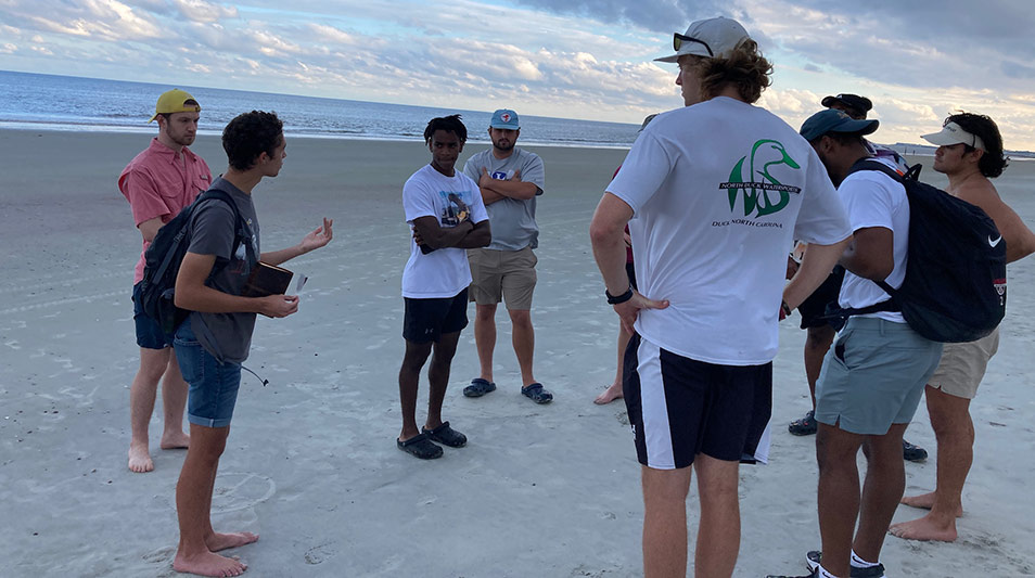 students standing on the beach talking