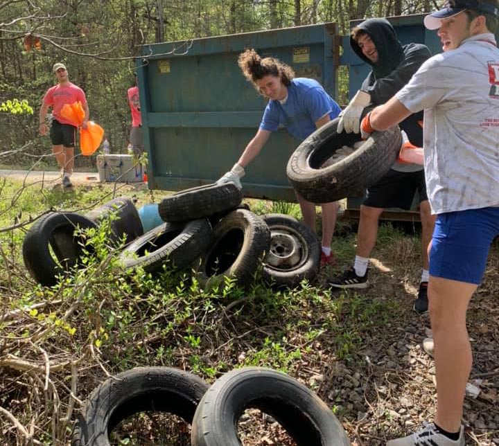 Hampden-Sydney students lifting tires out of a pile of debris