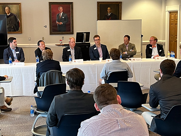 Alumni guest speakers sit on a panel in front of a student audience
