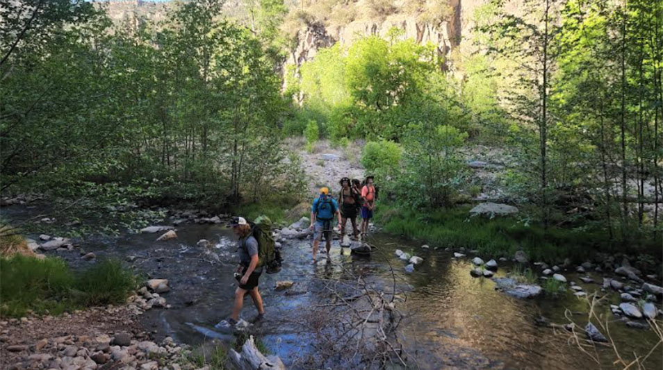 Hampden-Sydney students hiking through a creek in the Gila Wilderness