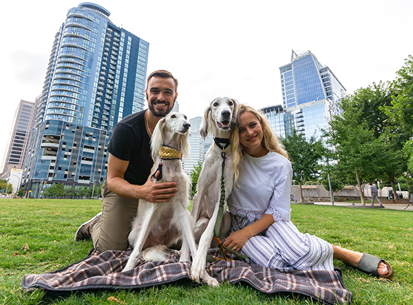 Yevhen (Zhenya) Goncharov with his wife and dogs posing on the lawn in a city
